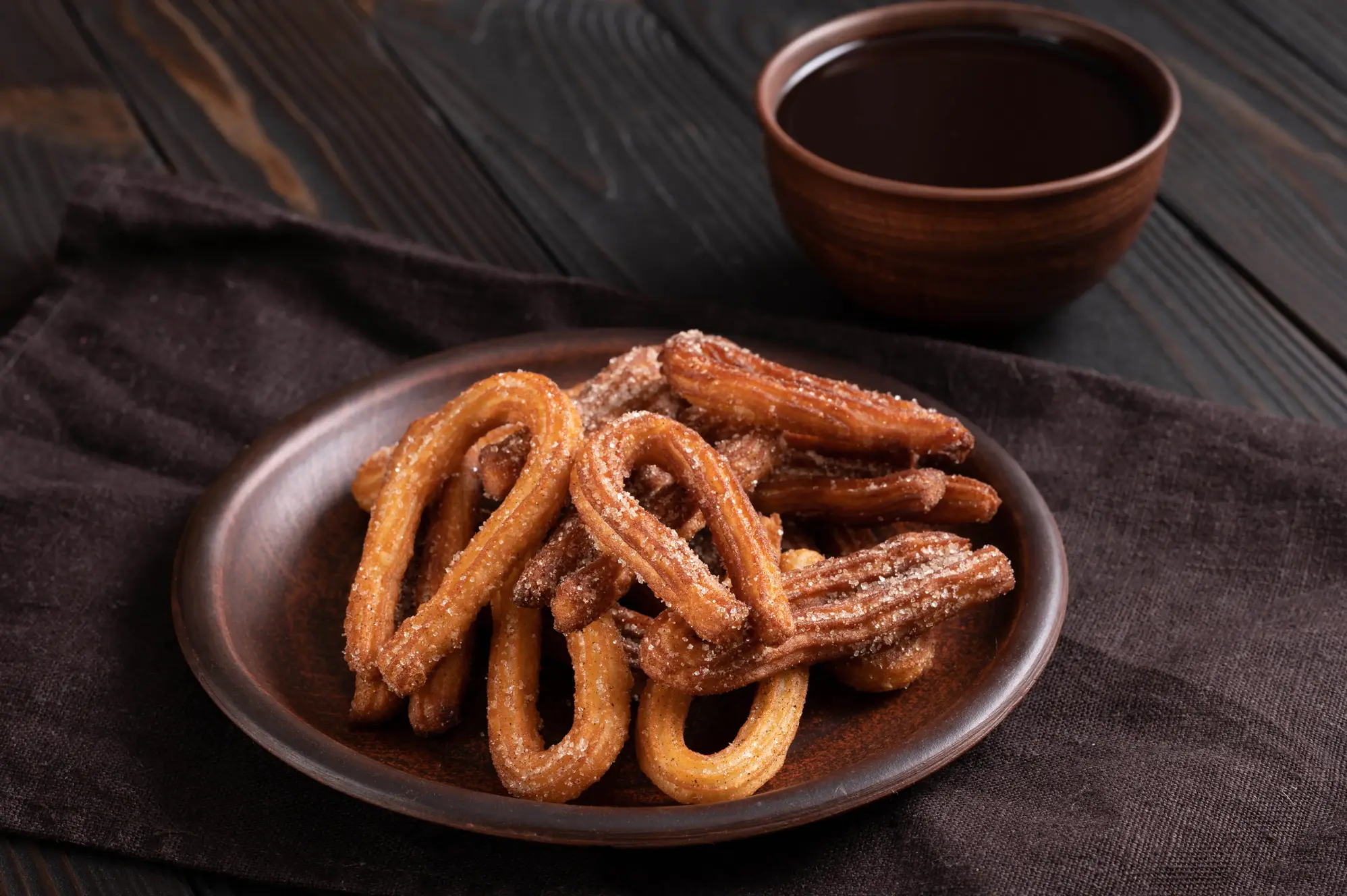 A pile of fresh churros with chocolate dip